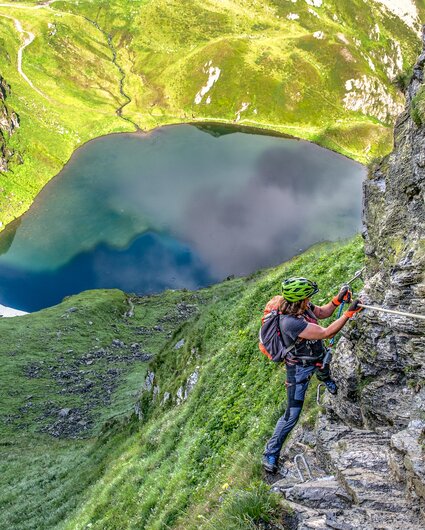 Eine Frau im Klettersteig oberhalb eines Bergsees in der Silvretta Montafon. | © Silvretta Montafon - Bertram Waldner