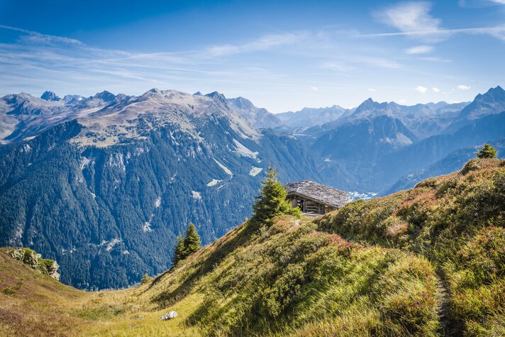 Ein Wanderweg mit schönem Panorama im Hintergrund und einer Hütte | © Silvretta Montafon - Marcel Mehrling