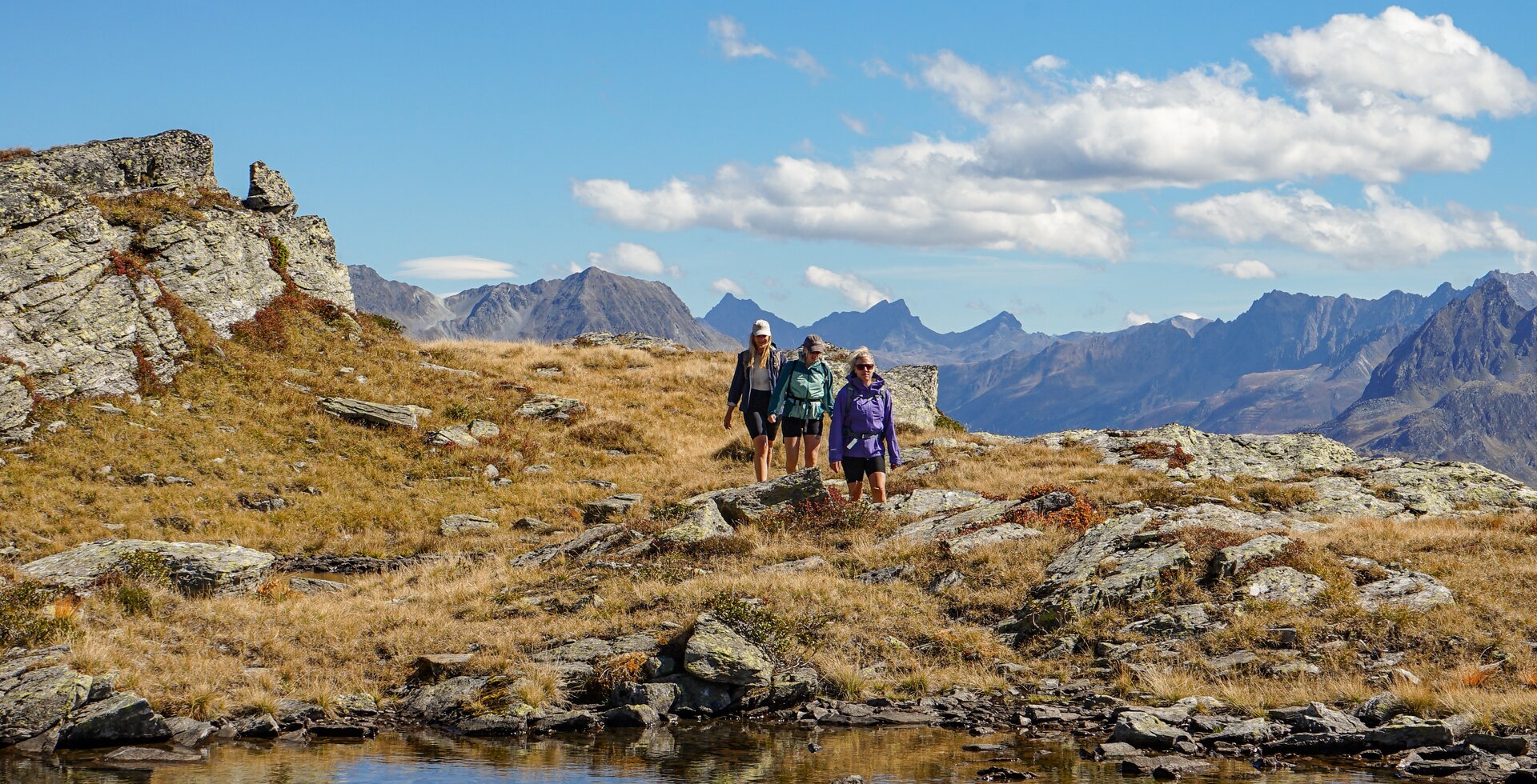 Drei junge Frauen wandern im herbstlichem Gebirge zu einem Bergsee. | © Silvretta Montafon - Vanessa Strauch