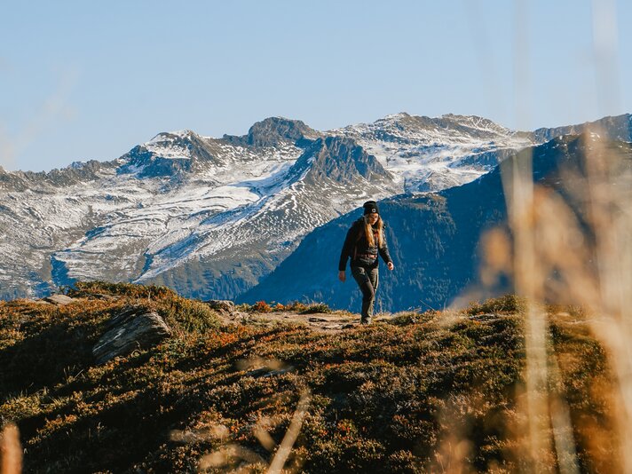 Eine Frau wandert im Herbst mit schneebedeckten Bergspitzen im Hintergrund in der Silvretta Montafon | © Silvretta Montafon - Vanessa Strauch