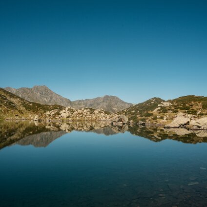 Der Alpgues See mit reflektierenden Bergen in der Silvretta Montafon. | © Silvretta Montafon - Vanessa Strauch