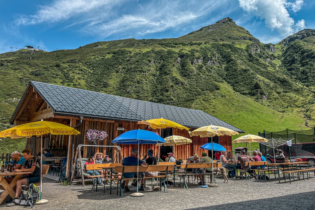 Eine Alpe in den Bergen mit gut besuchter Terrasse. | © Silvretta Montafon - Vanessa Strauch