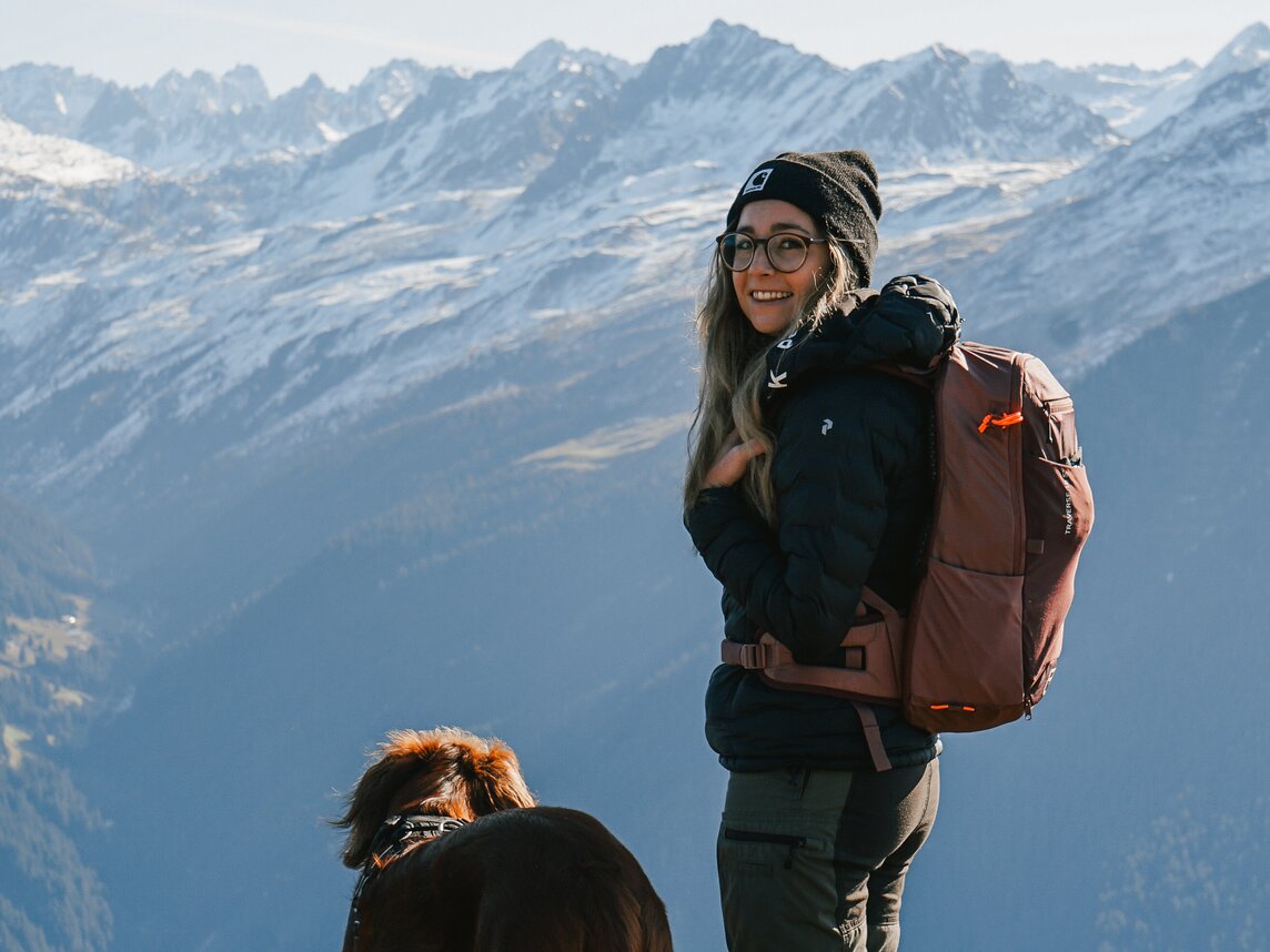 Eine Frau und ihr Hund genießen die Aussicht auf die Gipfel der Silvretta Montafon bei einer Wanderung im Herbst | © Silvretta Montafon - Vanessa Strauch
