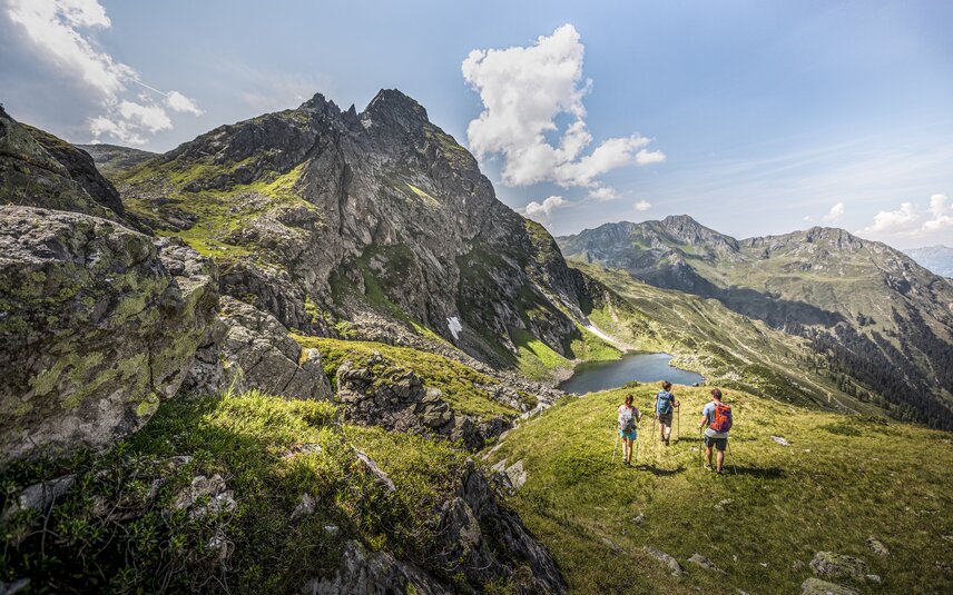 Drei Personen wandern Richtung Herzsee im Sommer am Hochjoch in der Silvretta Montafon. | © Silvretta Montafon - Stefan Kothner