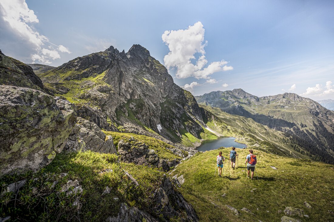 Drei Personen wandern Richtung Herzsee im Sommer am Hochjoch in der Silvretta Montafon. | © Silvretta Montafon - Stefan Kothner