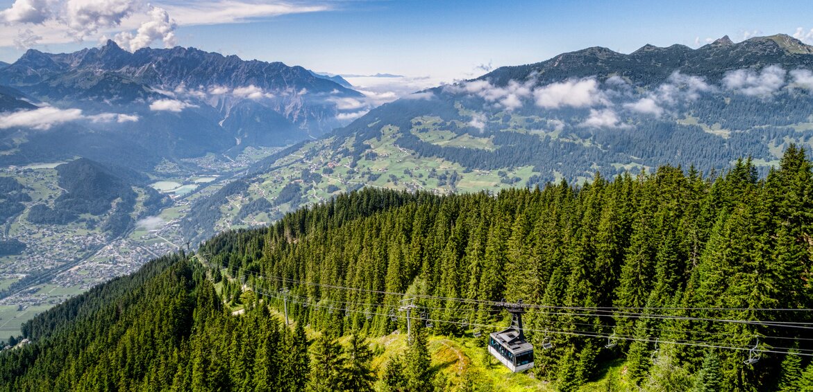 Ein dichter grüner Wald im Sommer mit der Hochjoch Bahn und Blick auf das Montafon | © Silvretta Montafon - Stefan Kothner