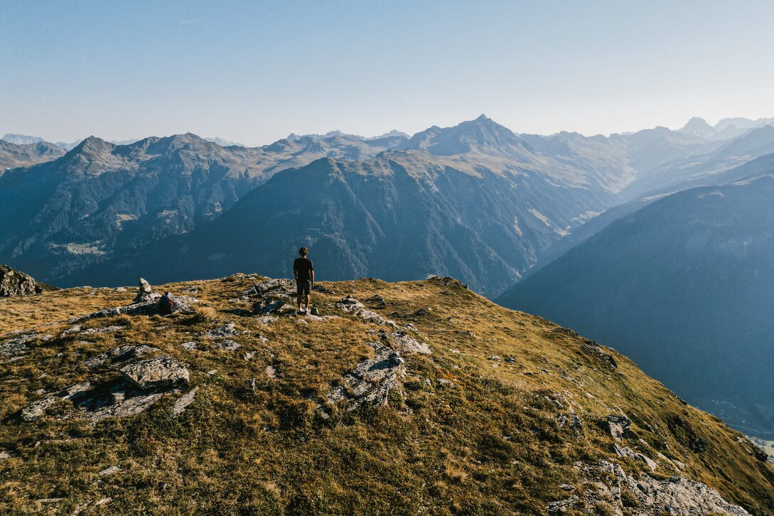 Ein junger Mann mit schwarzer Wanderkleidung und Sonnenbrille genießt die Aussicht auf die Montafoner Bergwelt in der Silvretta Montafon | © Silvretta Montafon - Vanessa Strauch