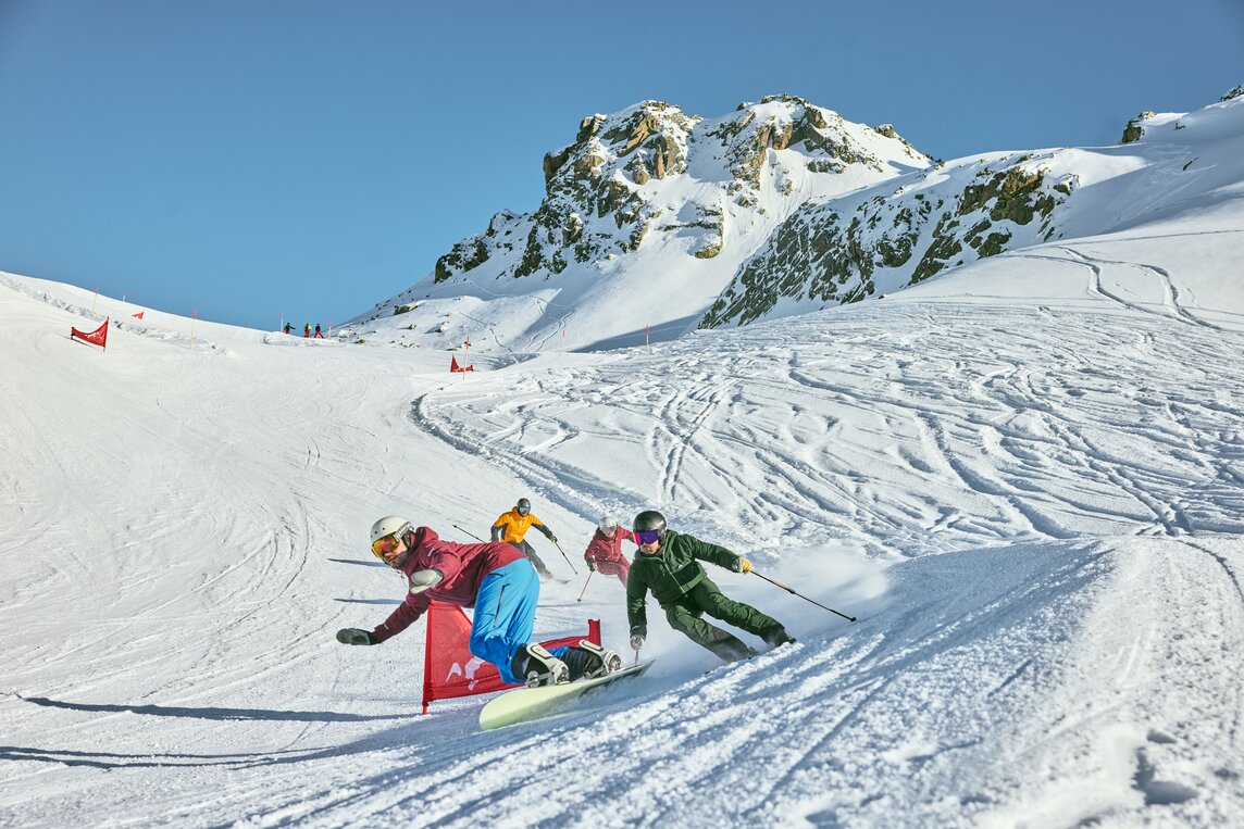 Eine Gruppe von Skifahrern und ein Snowboarder auf der Piste im Race Cross in der Silvretta Montafon. | © Silvretta Montafon - Stefan Kothner