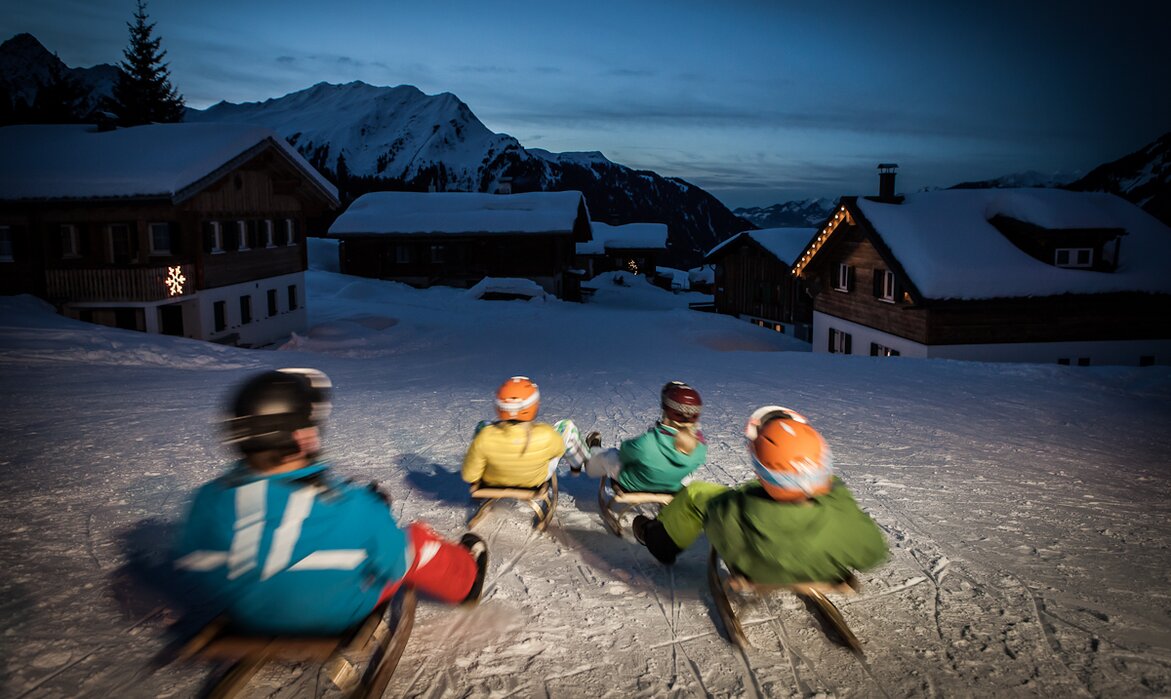 Vier Freunde auf dem Schlitten rodeln über die Nachtrodelbahn Garfrescha in der Silvretta Montafon  | © Silvretta Montafon - Daniel Zangerl