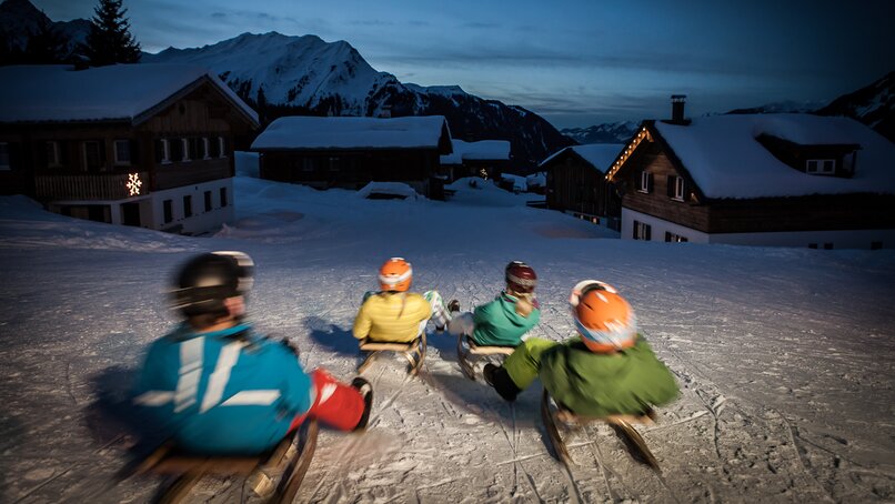 Vier Freunde auf dem Schlitten rodeln über die Nachtrodelbahn Garfrescha in der Silvretta Montafon  | © Silvretta Montafon - Daniel Zangerl