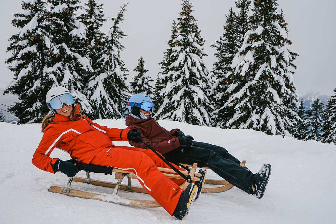 Zwei Freunde lachen beim Rodeln auf der Naturrodelbahn Kapell in der Silvretta Montafon | © Silvretta Montafon - Vanessa Strauch