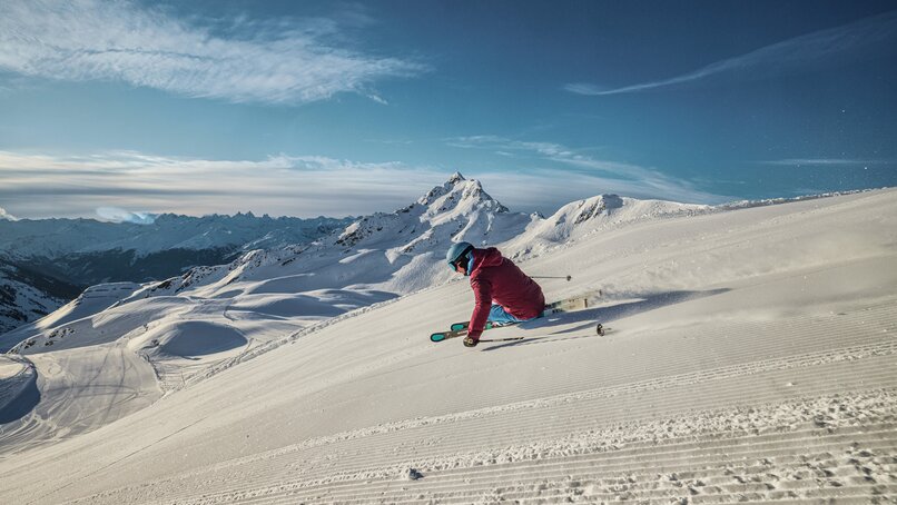 Ein Skifahrer fährt am Morgen über die frisch präparierte Piste mit der Zamangspitze im Hintergrund. | © Silvretta Montafon - Stefan Kothner