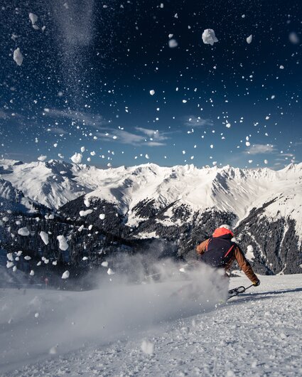 Ein Skifahrer auf der Piste und spritzender Schnee im Vordergrund. | © Silvretta Montafon - Daniel Hug