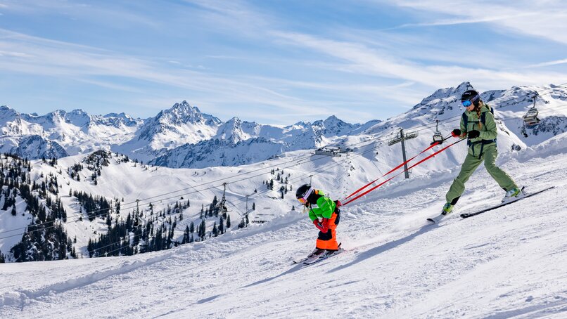 Eine Mutter übt mit Ihrem Kind am Gurt den Pflug beim Skifahren in der Silvretta Montafon. | © Silvretta Montafon - Torsten Wenzler