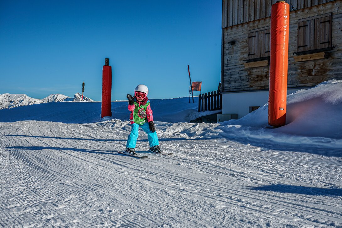 Ein Kind fährt auf den Ski im Kinderland und winkt in die Kamera. | © Silvretta Montafon - Vanessa Strauch