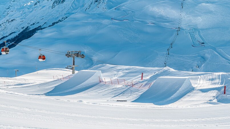 Zwei Kicker im Snowppark Montafon und die Hochalpila Bahn im Hintergrund. | © Silvretta Montafon - Matty Cox