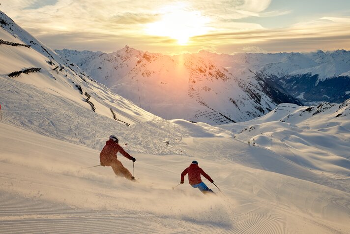 Zwei Skifahrer fahren über die frisch präparierte Piste bei Sonnenaufgang bei der HochjochTotale in der Silvretta Montafon | ©  Silvretta Montafon - Stefan Kothner