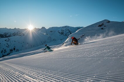 Zwei Skifahrer gleiten über die frisch präparierten Pisten bei Sonnenaufgang bei der Nova Exklusiv in der Silvretta Montafon | © Silvretta Montafon - Daniel Hug