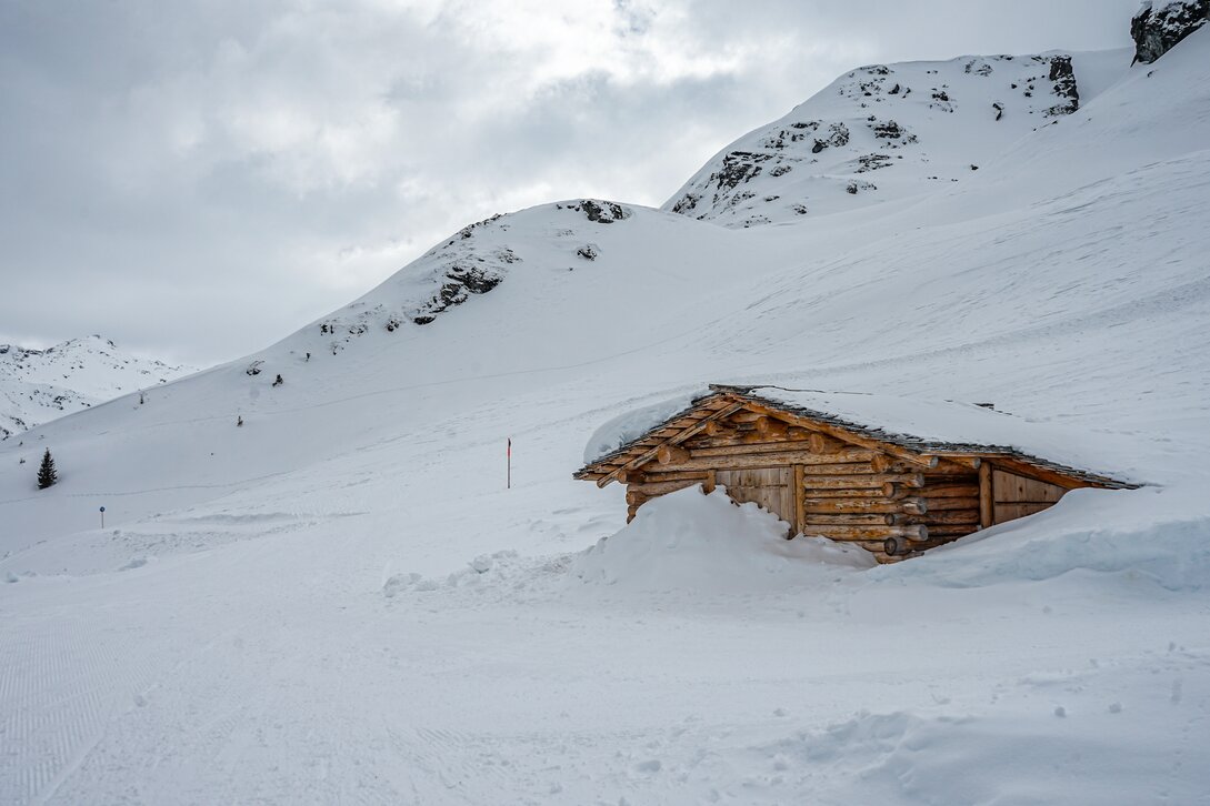Verschneiter Winterwanderweg und eine Holzhütte in den Bergen der Silvretta Montafon. | © Silvretta Montafon - Vanessa Strauch