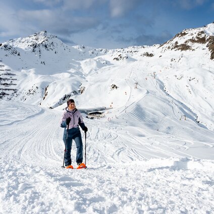 Eine Frau mit Schneeschuhen läuft auf einem Scheeschuhwanderweg in verschneiter Natur hoch oben am Berg. | © Montafon Tourismus - Andreas Marent