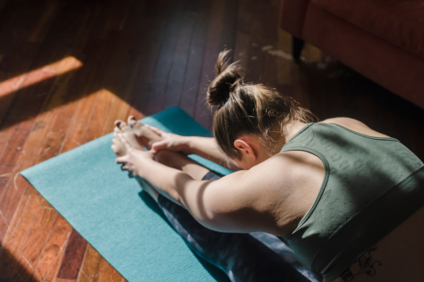 Eine Frau macht eine Yoga-Übung auf einer Matte | © Tina Fehrenbach - Silvretta Montafon