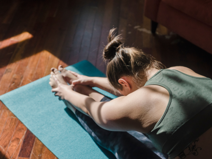 Eine Frau macht eine Yoga-Übung auf einer Matte | © Tina Fehrenbach - Silvretta Montafon