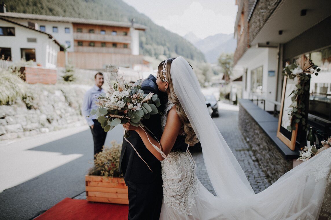 Eine Braut und ihr Bräutigam umarmen sich nach der Hochzeit vor der Stoba 7 | © Silvretta Montafon - Cornelius Lorünser