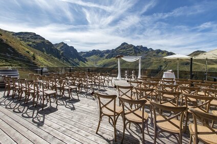 Dekorierter Traubogen und Bestuhlung für eine Hochzeit auf der Terrasse der VINNOVA mit Berge im Hintergrund | © Silvretta Montafon - Patrick Säly