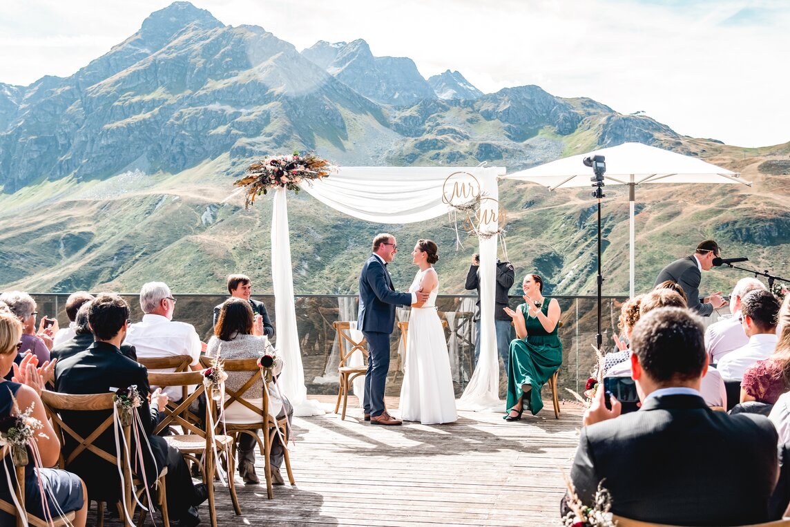Eine Paar gibt sich das Ja Wort vor den Gästen mit traumhaften Blick auf die Bergkulisse im Hintergrund | © Silvretta Montafon - Stefan Kothner