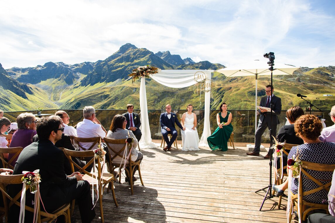 Die Gäste und das Brautpaar während der Trauung auf der Terrasse der Vinnova mit unglaublichen Ausblick auf die dahinterliegende Bergwelt | © Silvretta Montafon - Stefan Kothner