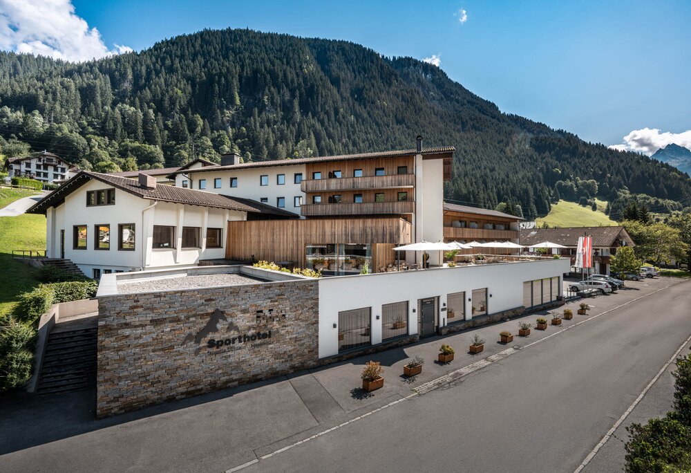 Sporthotel Silvretta Montafon im Sommer | © Silvretta Montafon - Mara Baues Sporthotel im Sommer mit grünen Bergen im Hintergrund und Sonnenschein | © Silvretta Montafon - Mara Baues