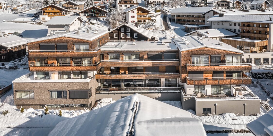 Das Sporthotel Silvretta Montafon schneebedeckt im Vordergrund mit weißen Bergen im Hintergrund | ©  Silvretta Montafon - blateral