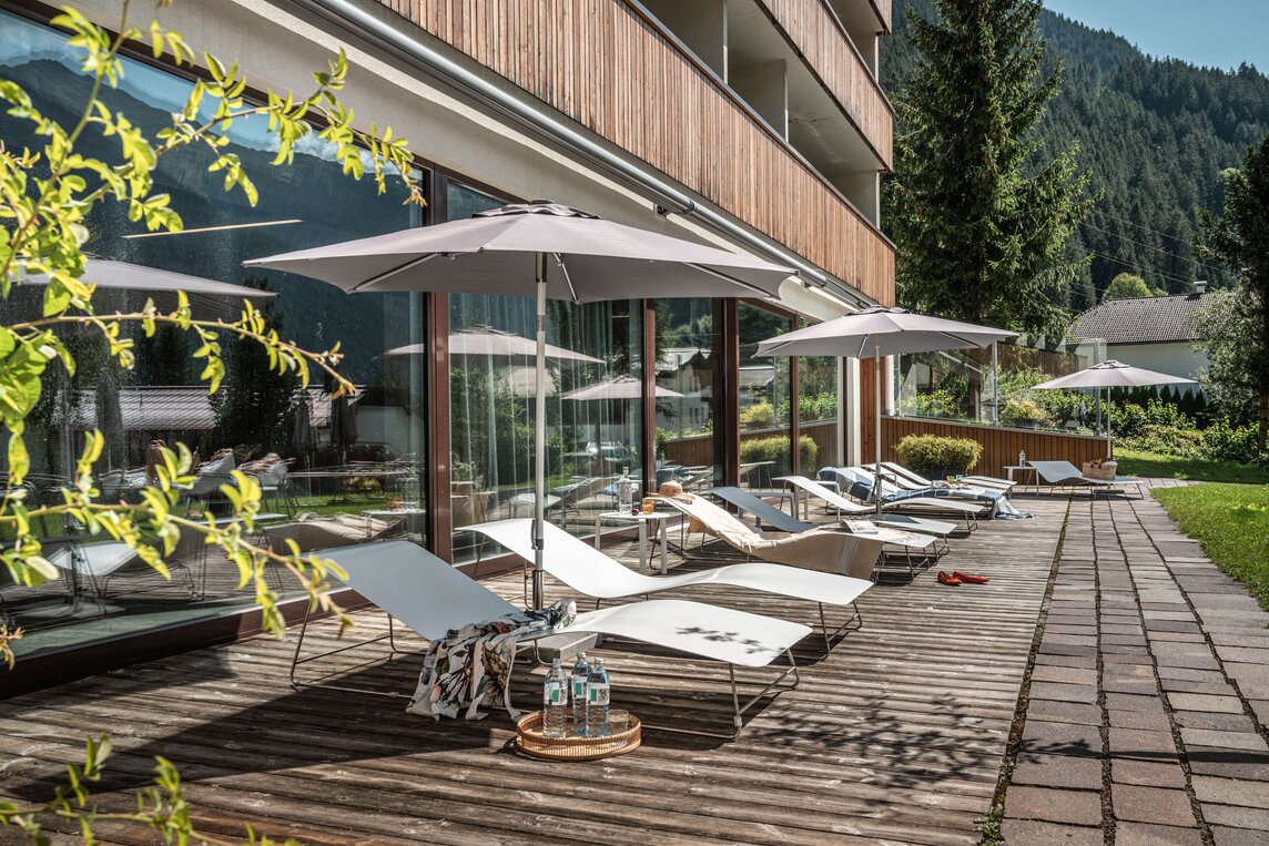Mehrere Sonnenliegen in der Sonne vor dem Spa Bereich im Garten des Sporthotels Silvretta Montafon | © Silvretta Montafon - blateral